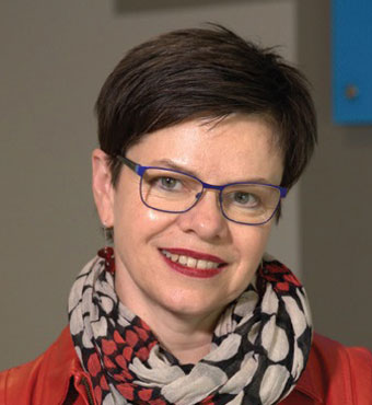 Head and shoulders of Professor Joanne Tompkins, Executive Director, Humanities and Creative Arts, wearing a red top with a red, beige and black patterned scarf around her neck.
