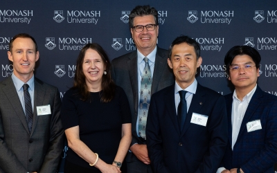Master of Ceremonies Prof Yiannis Ventikos, Dr Matthew French, ARC Academic Director Alison Ross, Director of NetZero Hub Prof Wenhui Duan standing in front of a Monash University branded backdrop. They are dressed in formal business attire and wearing name badges, posed for a group photo.