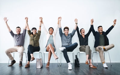 Studio shot of a group of businesspeople holding hands and cheering in a waiting room