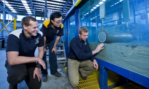 Researchers with subsea pipeline in the lab