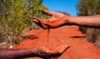 hands sifting red dirt 