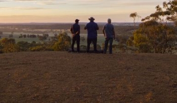 3 people silhouetted looking out at country landscape