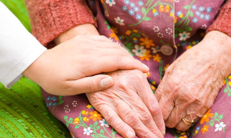 Young hand holding older woman's hand