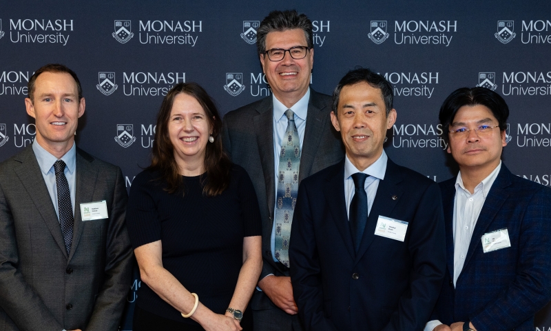 Master of Ceremonies Prof Yiannis Ventikos, Dr Matthew French, ARC Academic Director Alison Ross, Director of NetZero Hub Prof Wenhui Duan standing in front of a Monash University branded backdrop. They are dressed in formal business attire and wearing name badges, posed for a group photo.