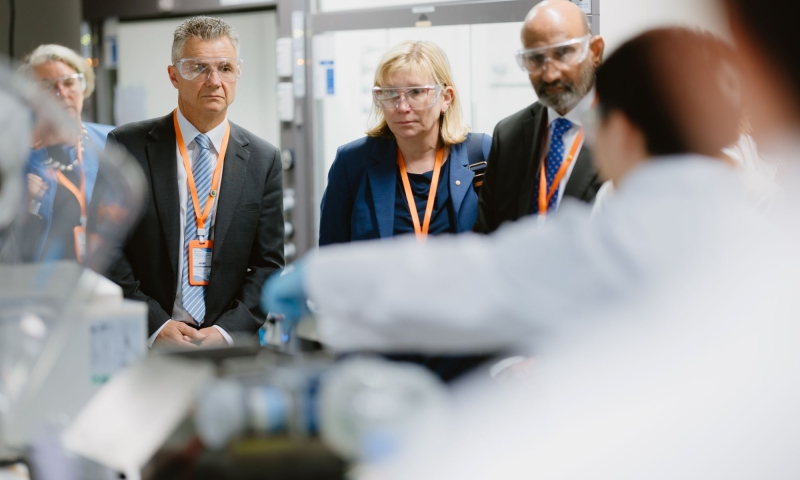 The Hon Matt Thistlethwaite MP, ARC CEO Professor Ute Roessner and Professor Chennupati Jagadish AC stand in a laboratory at UNSW wearing safety glasses while observing research equipment during a site visit following the PVRS hub launch.