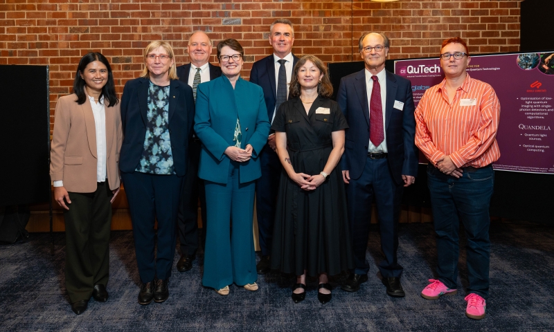ARC CEO, Prof Ute Roessner and distinguished guests standing side by side indoors in front of a brick wall, posing for a group photo.