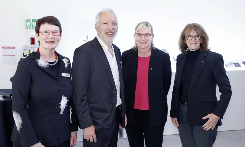 Four people standing indoors at the FLiQC launch event, facing the camera.